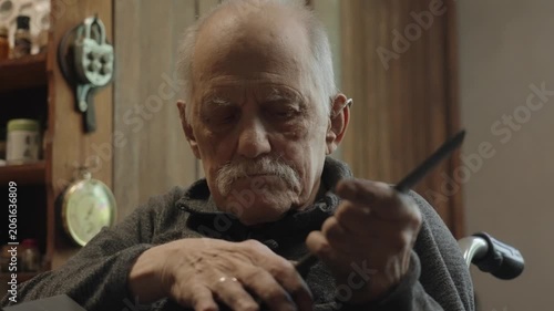 Elderly craftsman working in his old workshop, carefully restoring collectible Japanese bladed weapons
