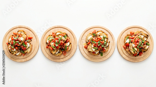 Four wooden plates of mixed vegetable salads with tomatoes, cucumbers, and herbs on a white background, healthy food arrangement.