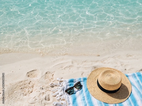 Straw hat and sunglasses resting on a tranquil beach