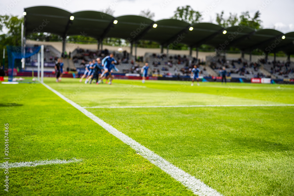 Obraz premium Goal line at first plane and blurred soccer players in action during match, real dynamic sports moment captured in stadium with crowd.