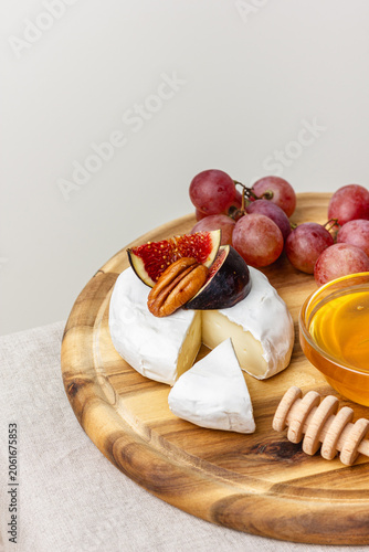 Appetizer board with meat, cheese, grapes, nuts, honey and fresh figs.