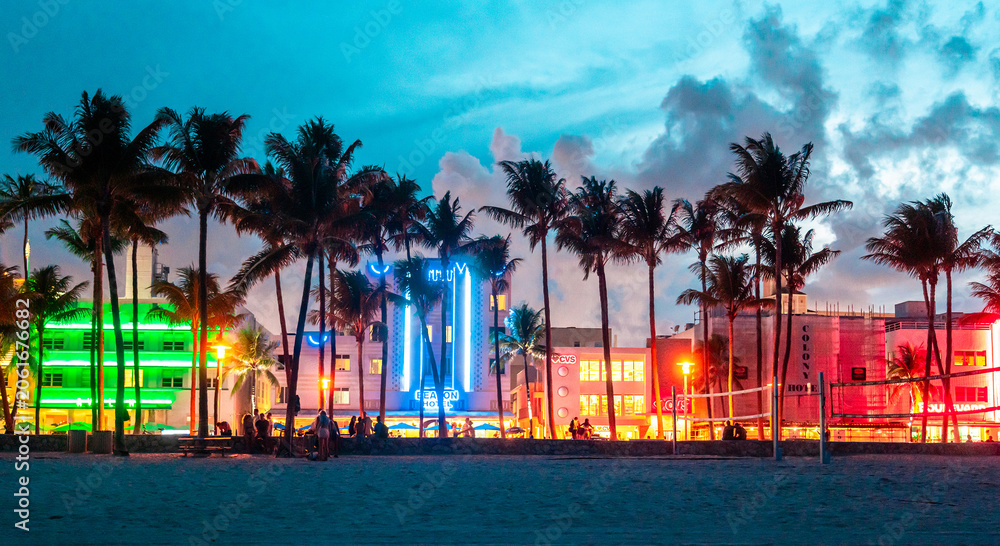 Fototapeta premium Miami Beach Ocean Drive hotels and restaurants at sunset. City skyline with palm trees at night. Art deco nightlife on South beach