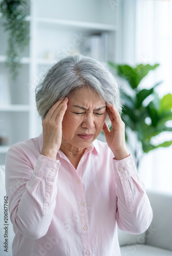 Elderly Asian woman touching temples in pain, dizziness and hypertension concept