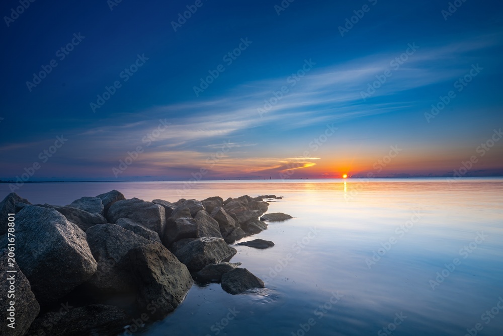 Fototapeta premium Dramatic sunset sky reflecting on calm ocean water at twilight