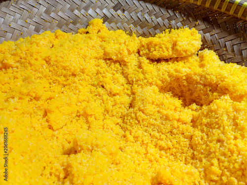 Indonesian traditional corn rice or nasi jagung inside woven bamboo winnowing basket. Textured yellow granular steamed maize meal closeup background.
