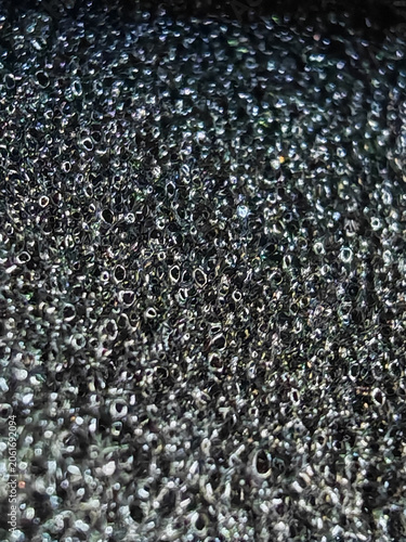 Dark alien organic structure texture, macro close-up of a black porous surface with deep shadows and intricate fibrous mesh pattern, moody atmospheric biological backdrop for creative designs