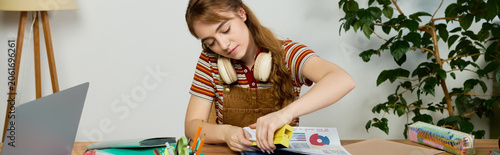Tablou pe pânză Young woman immersed in creative study at her cozy desk filled with art supplies