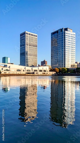 A serene cityscape with two sleek skyscrapers reflected in calm water
