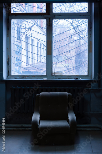 Dark empty room with armchair standing back to window