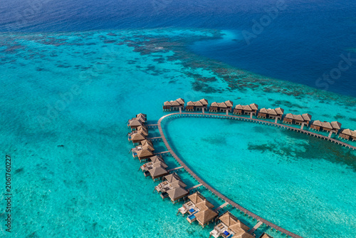 Quadro em tela Aerial view of curved overwater villas in the Maldives, thatched roofs and private decks, some with plunge pools, bright daylight, sandbanks and coral, calm lagoon arc
