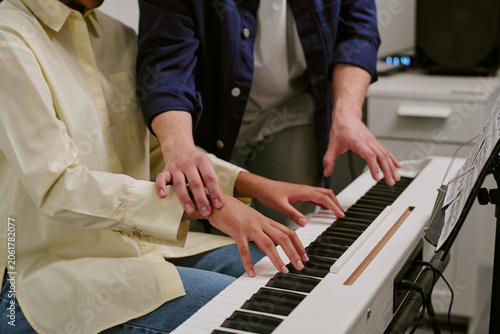 Photos Teenager practicing piano with instructor guiding hand position on keyboard, showing music education and skill development