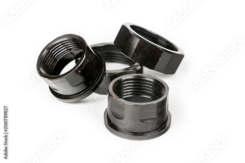 Large metal nuts painted black. Four large metal nuts. Close-up on a white background.