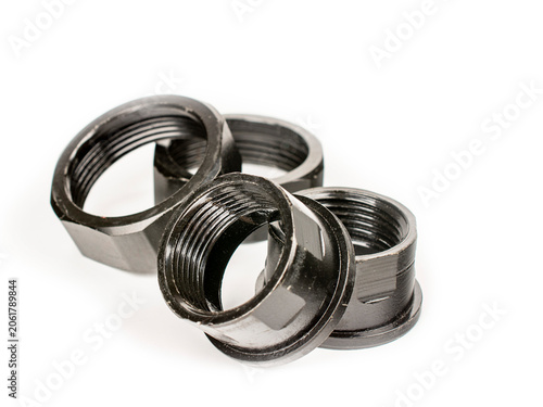 Large metal nuts painted black. Four large metal nuts. Close-up on a white background.