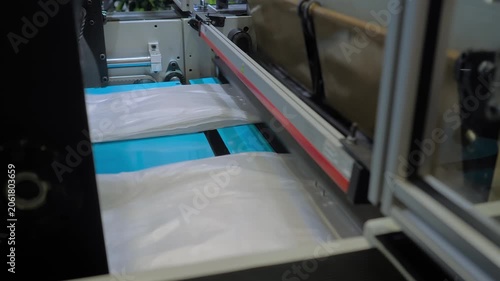 Automatic plastic bag making and cutting machine - production of packaging white bags at exhibition, factory: close up. Recycling, industry, manufacturing, and technology equipment concept