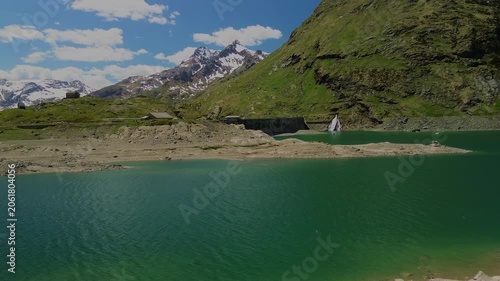 Woman standing on rocks by a turquoise alpine lake with mountains