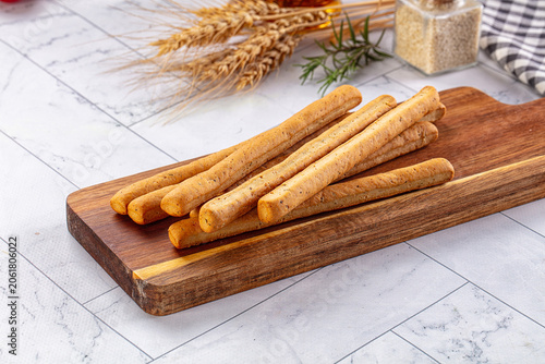 Bild auf Leinwand Italian breadsticks grissini on wooden board with wheat and rosemary