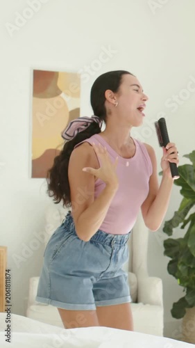 Vertical video: Singing woman in mauve top holding remote mic at home for pal with phone appearing
