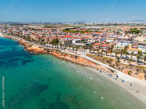 Aerial view Torre de la Horadada townscape with Mediterranean  Sea,  residential buildings, palm tree lined promenade and sandy beach. Costa Blanca, Alicante province, Spain