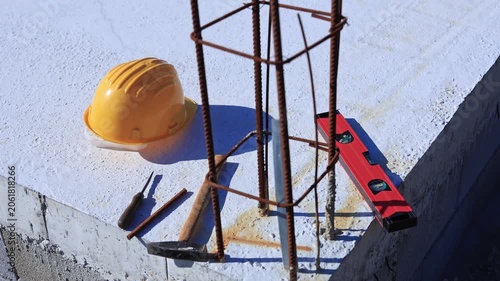 Construction tools and helmet on a cement foundation with iron rebar.