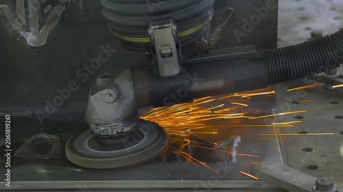 Robotic grinding system with angle grinder is processing the metal material surface, producing a lot of sparks - close up. Industrial, metalworking, manufacturing, processing, and equipment concept