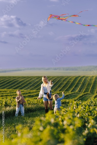 Happy children running with mother flying kite
