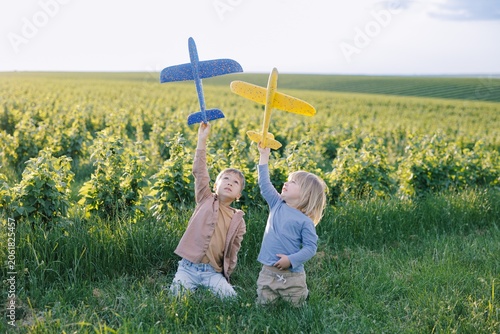 Children playing with toy gliders in green field