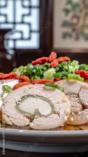 Vertical video: Sliced Chinese chicken roll garnished with goji berries and green scallions on a plate. Traditional asian cold appetizer closeup footage