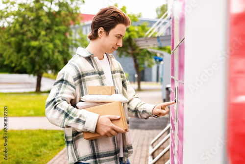 Canvastavla a man holding packages uses an automated parcel locker terminal for a contactless delivery pickup, highlighting modern logistics and ecommerce online shopping