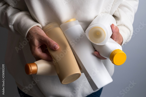 Person holding multiple plastic cosmetic bottles, plastic waste and recycling concept

