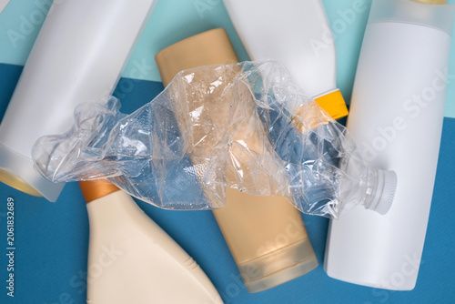 Crushed plastic bottle on top of assorted cosmetic containers, plastic waste and recycling concept