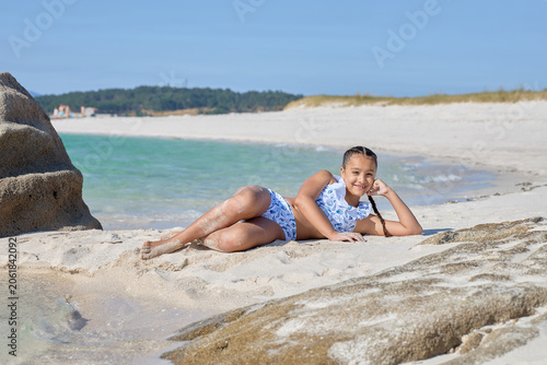 Girl Lying On Sandy Beach Near Rocks