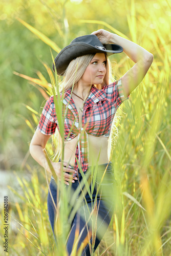 Woman holding hat in tall grass