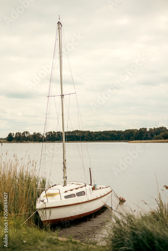 Small yacht moored along the shore of a peaceful lake