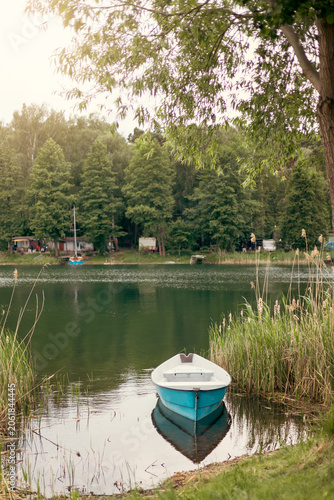 solitary wooden boat resting along the shore of a picturesque lake, surrounded by calm water and natural scenery