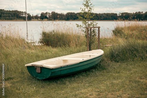 solitary wooden boat resting along the shore of a picturesque lake, surrounded by calm water and natural scenery