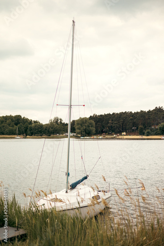 Small yacht moored along the shore of a peaceful lake
