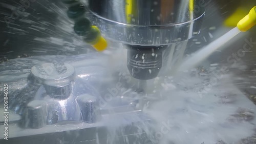 CNC turning milling machine with water cooling system is cutting metal workpiece in slow motion at factory, exhibition, plant: close up. Industrial, equipment, manufacturing, and metalworking concept