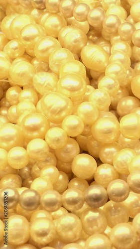 Close-up of creamy pearl strands and loose pearls shimmering with subtle movement in a dense jewelry background