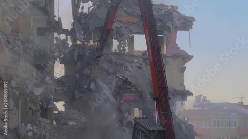 Excavator with hydraulic crusher is tearing down the old typical Turkish multi-storey apartment, residential building in Istanbul, Turkey - slow motion, demolition of building