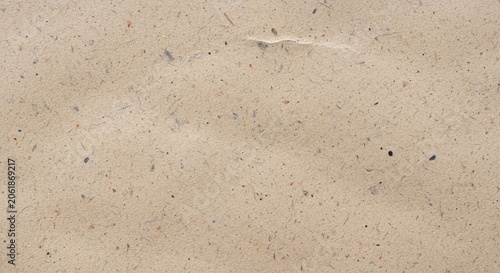 Closeup of a textured beige recycled paper background with small dark flecks and fibers