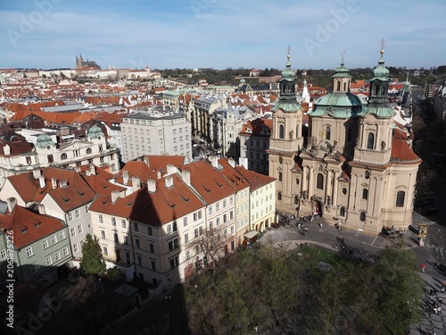 Aerial view of Prague: historic buildings with tiled roofs, Prague Castle, and city skyline on a clear sunny day. Landmarks and historic architecture of Prague, Czech Republic.