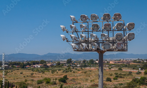 Konstfotografi Large stadium floodlight tower with multiple lamp heads rising above a rural Spa