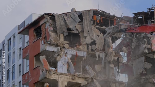 Slow motion: demolition of building, excavator with hydraulic crusher is tearing down the old typical Turkish multi-storey apartment, residential building in Istanbul, Turkey