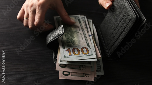 Φωτογραφία Woman's Hands Open A Black Leather Wallet And Remove Us Dollar Bills