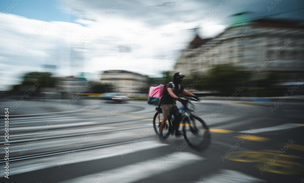 Naklejka premium Food Delivery Bicyclist Rides Fast Along A Bike Path City In Motion Rushing By In A Blur
