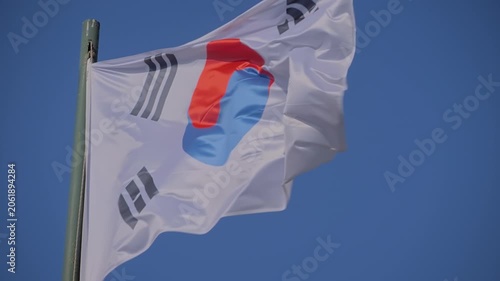 Taegeukgi - the national flag of South Korea is fluttering in the wind against the clear blue sky - slow motion. Freedom, politics, patriotism, diplomacy and international affairs concept