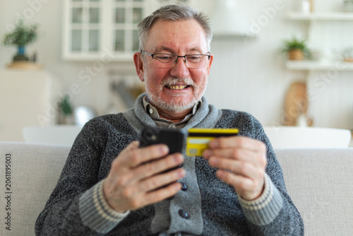 Billede på lærred Senior man shopping online holding smartphone paying with credit card