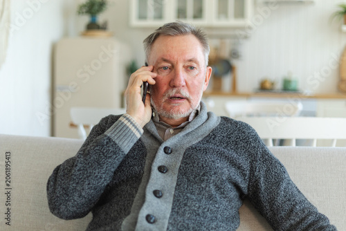 Happy middle aged senior man talking on smartphone with family friends. Older mature grandfather with cell phone talking with grown up children, resting at home. Older generation modern tech usage
