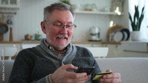Senior man shopping online holding smartphone paying with credit card. Old grandfather buying on Internet enter credit card details. Online shopping delivery service Older generation modern tech usage