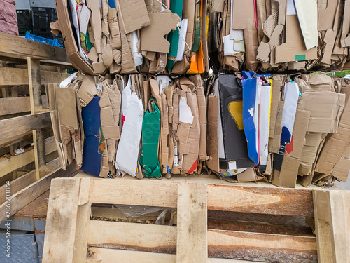 Stack of compressed cardboard bales on wooden pallets. Crushed paper boxes prepared for recycling and waste management